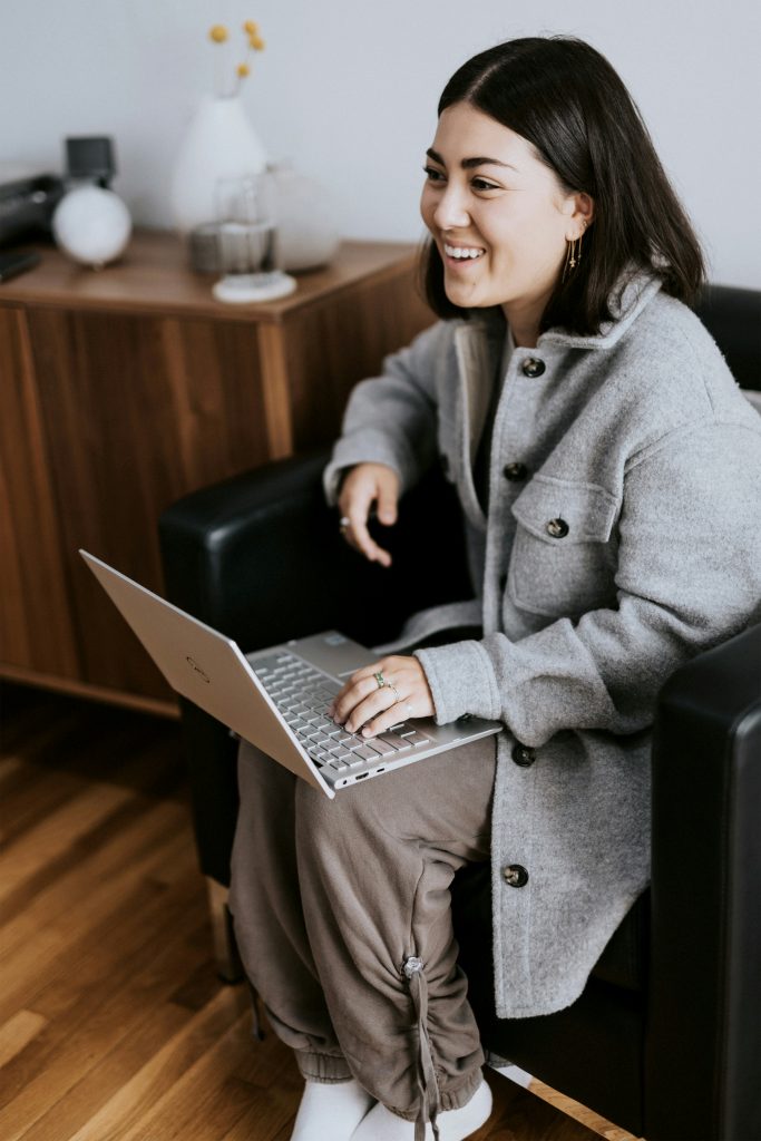 Frau Anfang 30, die am Laptop ihren Online-Coaching-Kurs verfolgt und sich begeistert darüber freut, ihre Traumkarriere in Deutschland voranzutreiben.